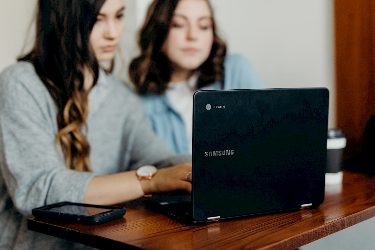Zwei junge Frauen sitzen an einem Laptop