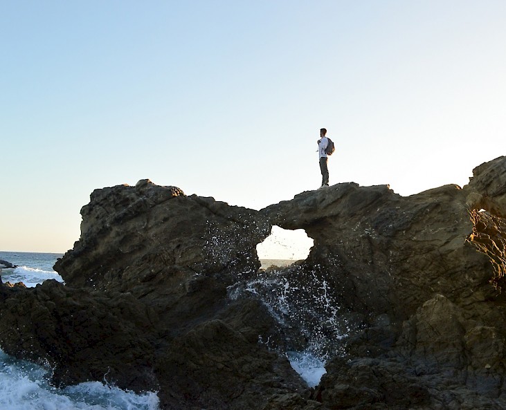 Junge steht auf einem Felsvorsprung am Meer