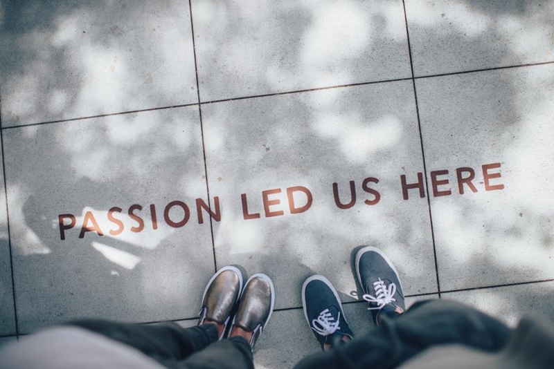 Blick auf die Füße von zwei Personen und die Aufschrift "Passion led us here" auf dem Fußboden