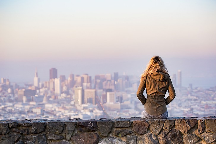 Ein Mädchen steht auf einer Aussichtsplattform vor der Skyline einer Großstadt