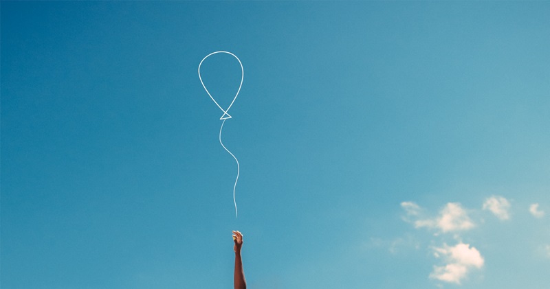 Ausschnitt einer Hand, die einen Luftballon wegfliegen lässt