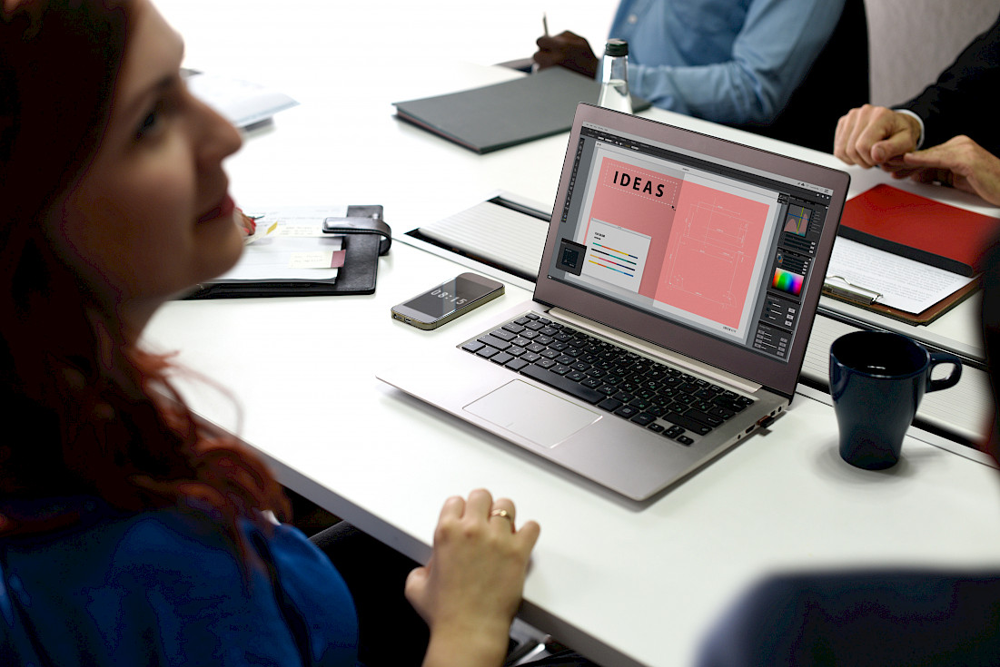 Frau sitzt an einem Laptop, auf dem ein Bild mit der Aufschrift "Ideas" geöffnet ist