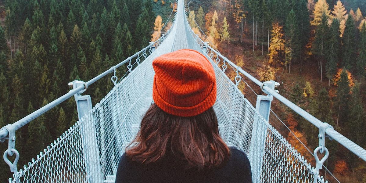 Junge Frau steht am Anfang einer großen Brücke