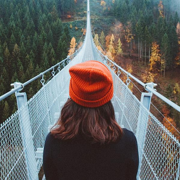 Junge Frau steht am Anfang einer großen Brücke