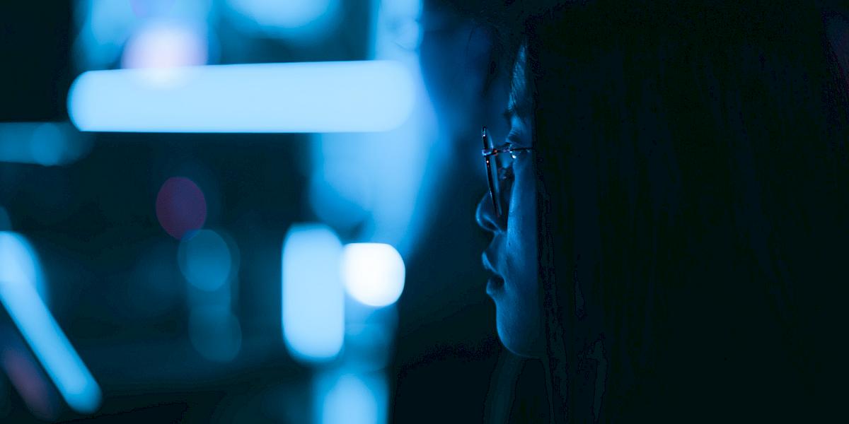 Mädchen mit Brille vor blauem Hintergrund schaut konzentriert nach vorne