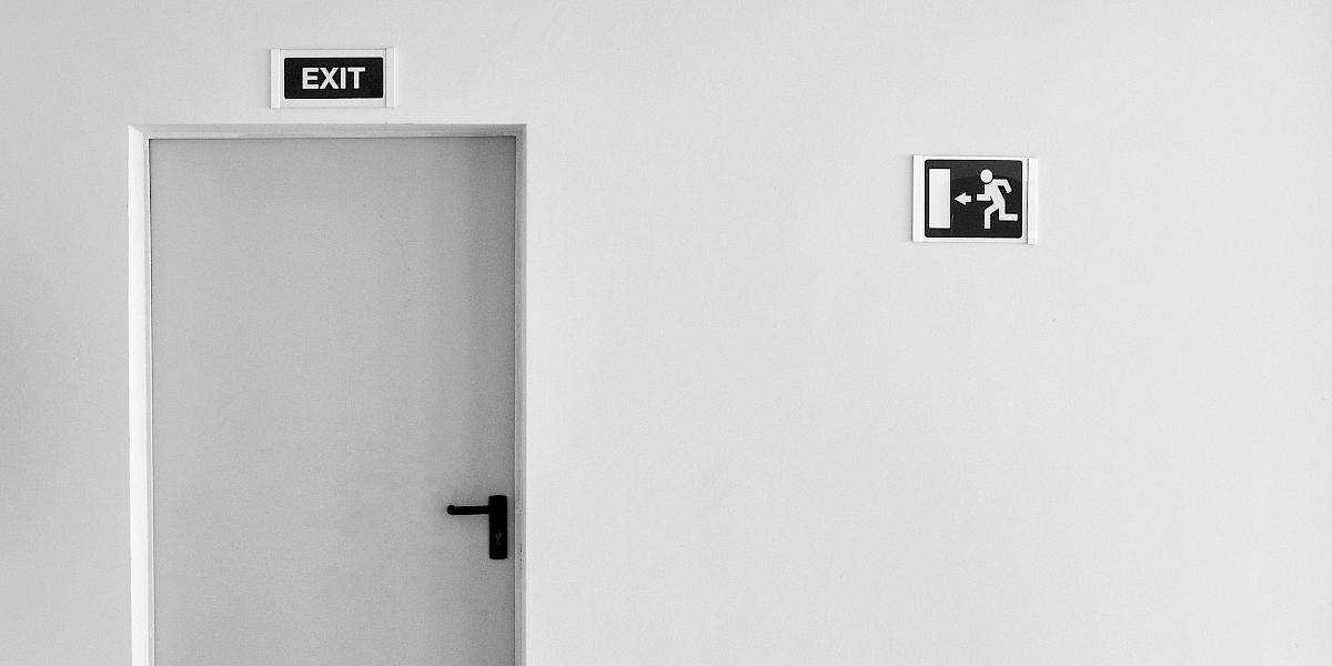 Eine Tür vor einer weißen Wand mit einem "Exit"-Schild darüber