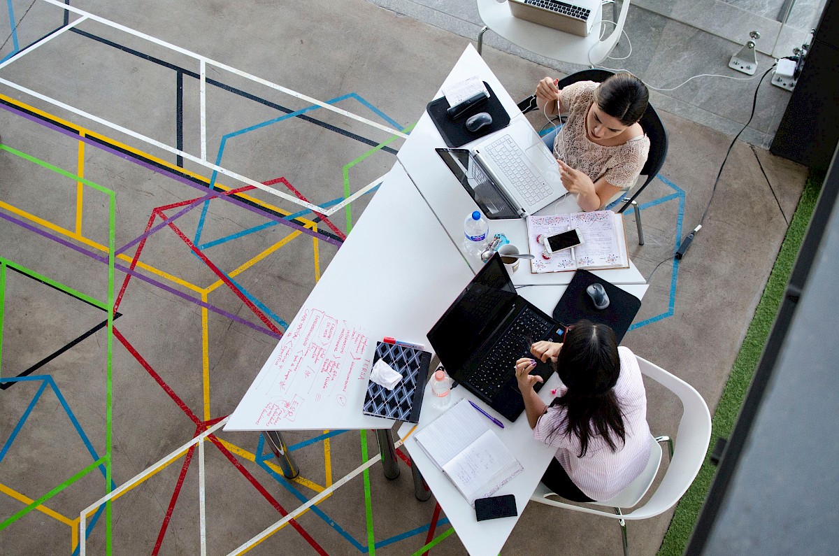 Zwei Frauen sitzen an einem Tisch in einem modernen Büro